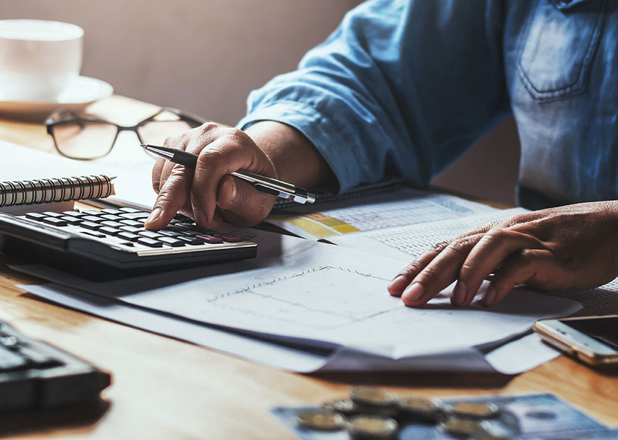 image of person working with a calculator and spreadsheets